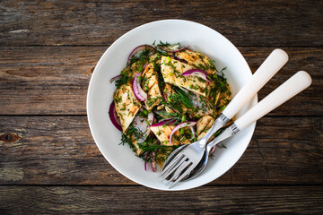 Marinated herring fillets with dill and red onion on wooden table
