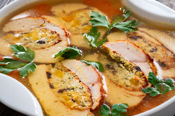 Baked stuffed turkey sliced fillet in jelly and vegetables on wooden table
