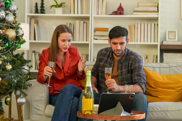 A man and woman clink champagne glasses in a convivial toast, surrounded by the warmth and joy of a homely Christmas setup, full of laughter and shared stories.