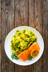 Pappardelle with grilled salmon steak and basil pesto on wooden table
