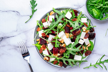Beetroot and white cheese salad with arugula, lettuce, chard and walnuts, white table, copy space. Fresh useful vegetarian dish for healthy eating - 783906215