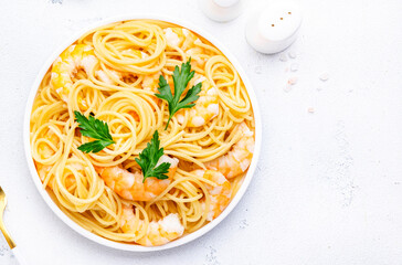 Delicious spaghetti pasta with big shrimp on plate with parsley, white table background. Top view - 783906667