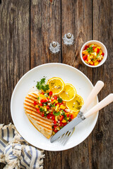 Grilled chicken breast and fresh vegetables on wooden table
