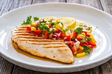 Grilled chicken breast and fresh vegetables on wooden table
