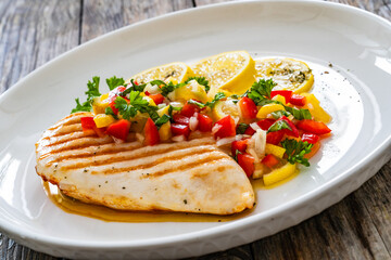 Grilled chicken breast and fresh vegetables on wooden table
