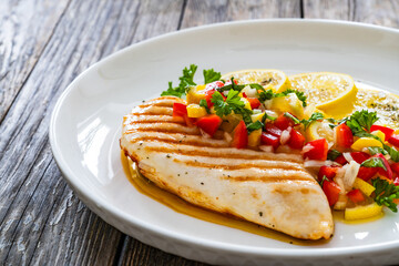 Grilled chicken breast and fresh vegetables on wooden table
