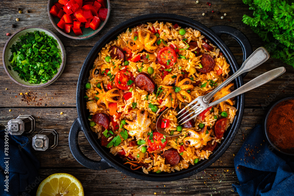 Wall mural paella seafood and chorizo in cooking pan on wooden table - Wall murals