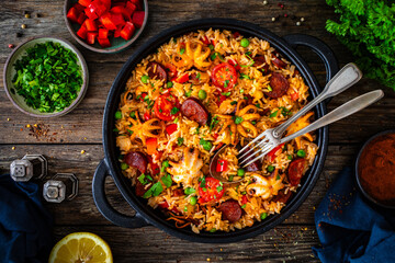 Paella seafood and chorizo in cooking pan on wooden table
 - obrazy, fototapety, plakaty