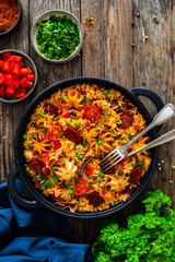 Paella seafood and chorizo in cooking pan on wooden table
