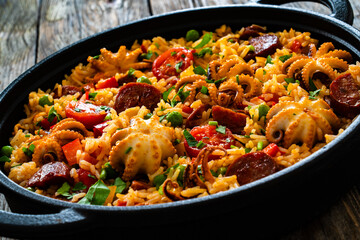 Paella seafood and chorizo in cooking pan on wooden table
 - obrazy, fototapety, plakaty