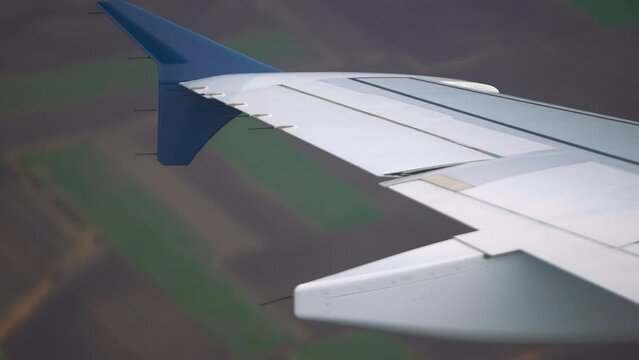 An aweinspiring aerial video of an airplane wing soaring above a vast field, accompanied by a tranquil shot from the window capturing the majestic motion of the wing