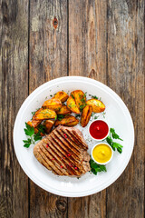 Grilled beef sirloin steak with baked potatoes on wooden table
