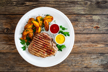 Grilled beef sirloin steak with baked potatoes on wooden table
