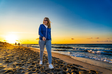 Beautiful mid adult woman walking on beach at sunset
