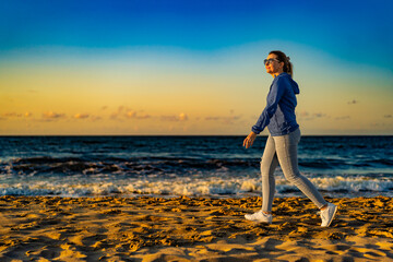 Beautiful mid adult woman walking on beach at sunset
