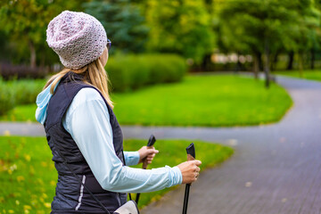 Nordic walking - woman exercising in city park
