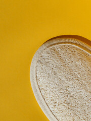 Top view of loofah sponge in yellow blank background. Natural Organic toiletries. Corporal Hygiene and exfoliation concept. Negative space for text.