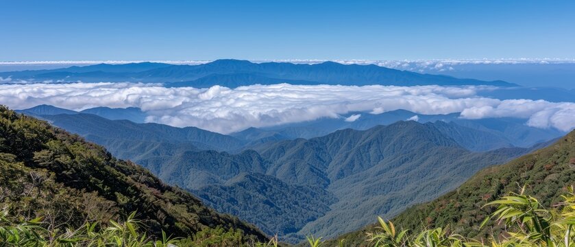   From a mountaintop, behold the vista of distant mountains and clouds against a backdrop of azure sky