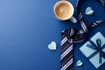 Father's day morning surprise concept. Top view of coffee, gift, and accessories on rich blue background