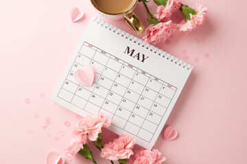 Celebrating mother's day: flat lay of may calendar with carnations and coffee on a pink background