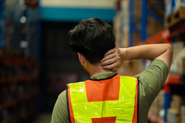 A man in a safety vest is looking down at his neck. He is wearing a yellow vest and has a black...