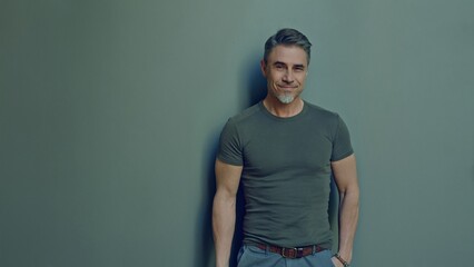 Portrait of a smiling middle-aged man. Happy, confident mid adult male in casual. Blank copy space on a gray wall background.