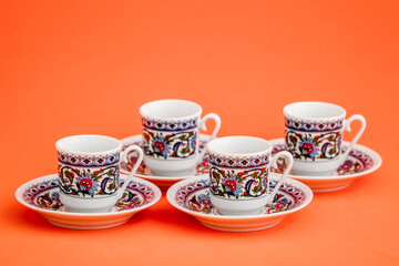 Classic porcelain Turkish coffee cups with floral design on orange background.