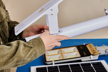 Assembling LED street lighting with solar panel, owner prepares mounting bracket.