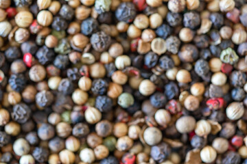 Set of peppercorns of different species and colors arranged in a disorderly, blurred way.