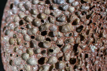 Dark pumice stone with visible irregularities in a circular shape.