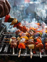 Foto op Aluminium Closeup of a hand grilling skewers of marinated meats and vegetables on a barbecue, with a smoky background © Pakorn
