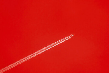 Airplane flying on red background with chemical direction trails