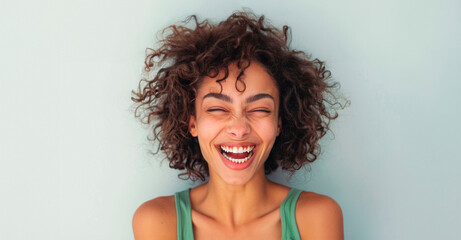 Joyful Young Woman Laughing Against a Serene Blue Background During Daytime - obrazy, fototapety, plakaty