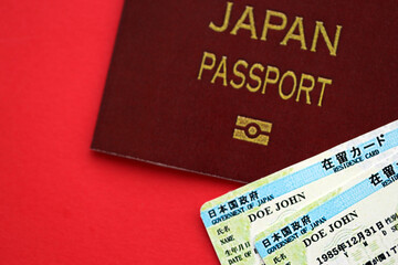 Green residence card of Japan with passport on red background close up