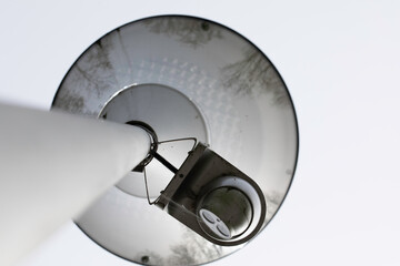 City surveillance camera with movable head, placed under the lamp shade