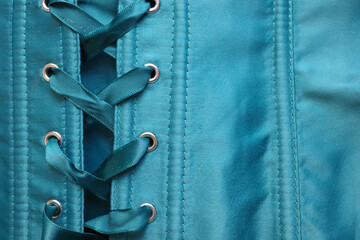 Close-up of the lacing ribbons of a turquoise corset