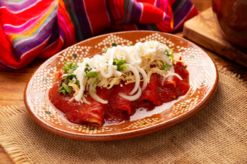 Entomatadas. Also known as Enjitomatadas, a typical dish of Mexican cuisine prepared with corn tortilla, tomato sauce and stuffed with shredded chicken meat. Classic homemade recipe. - 783961445