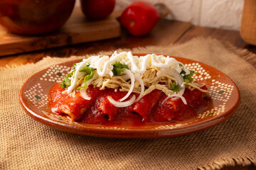 Entomatadas. Also known as Enjitomatadas, a typical dish of Mexican cuisine prepared with corn tortilla, tomato sauce and stuffed with shredded chicken meat. Classic homemade recipe.