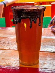 Xochimilco, Mexico City, Mexico - A Michelada beer in a large plastic cup on one of the canal boats
