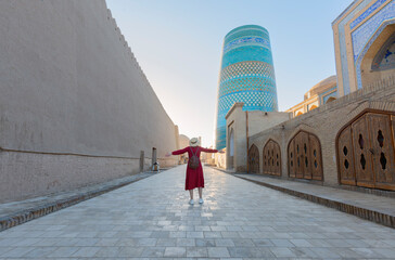 Young lady taking a picture of oriental buildings in Itchan Kala ancient town. Khiva, Uzbekistan