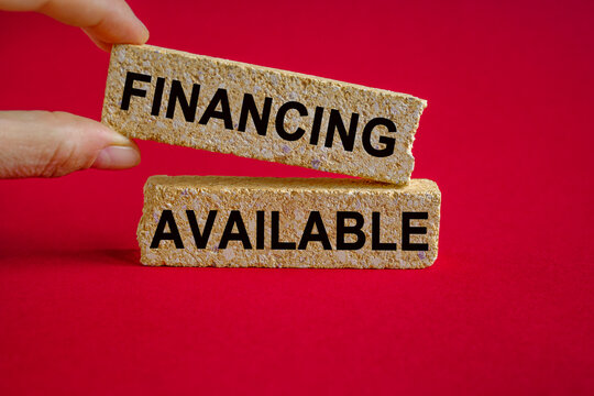 Financing available symbol. Concept words Financing available on brick blocks. Businessman hand. Beautiful red background. Business and financing available concept.