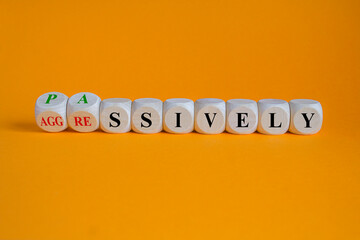 Turned wooden cubes and changes the word passive to aggressive. Beautiful orange background, copy...