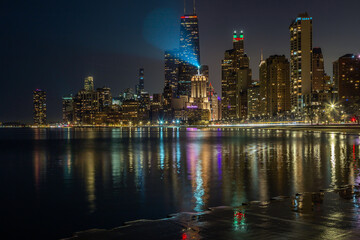 The Chicago skyline and waterfront at night with illuminated buildings reflected in the water of Lake Michigan