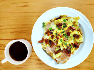 Top view of complete Omelette with bacon, ham, cheese and mug of coffee on the wooden background 