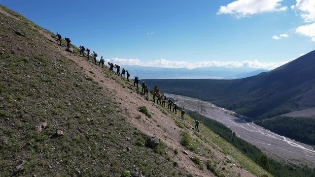 A group of tourists climb a mountain in summer. 