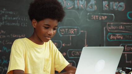 Smart african boy programing system or coding system by using laptop. Skilled highschool student...
