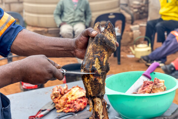 cleaning cow heels with a knife to cook ,traditional event, outdoors kitchen africa