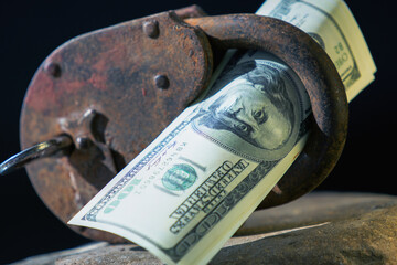 Massive metallic padlock and US Dollar bundle as symbol of investment security. Horizontal image.