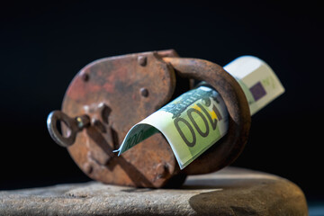 Closeup of massive metallic padlock and US Dollar bundle as symbol of investment security - 783992474