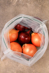 Various varieties of onions in fabric packaging. Healthy natural products in an eco bag to boost...